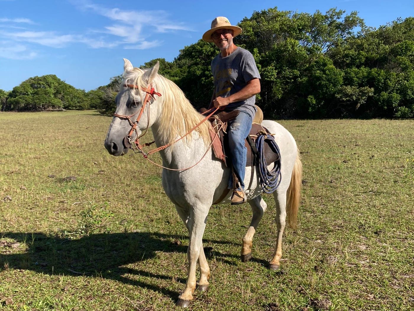 Cavalo selado no pasto do Rancho Aroeira, com o cavaleiro montado sob o céu aberto